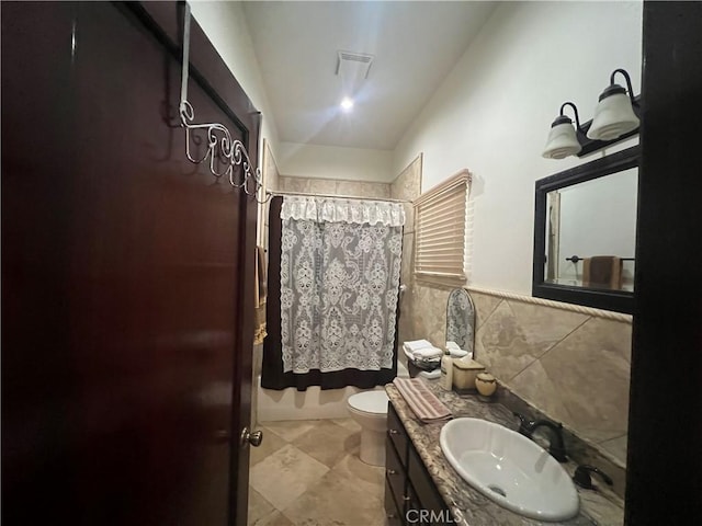 bathroom with toilet, visible vents, tile walls, and vanity