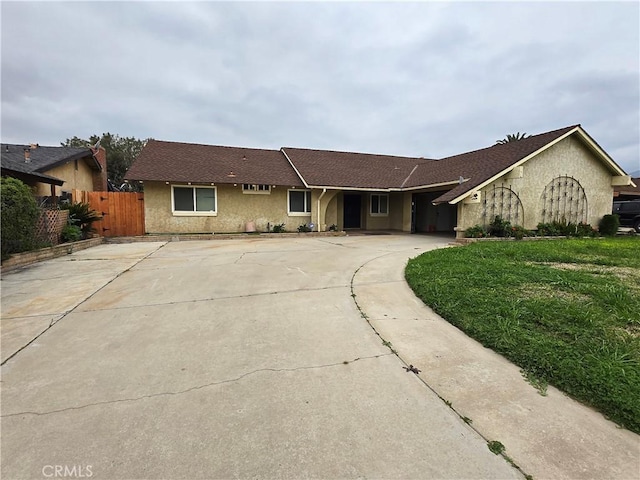 ranch-style house with driveway, fence, a front lawn, and stucco siding