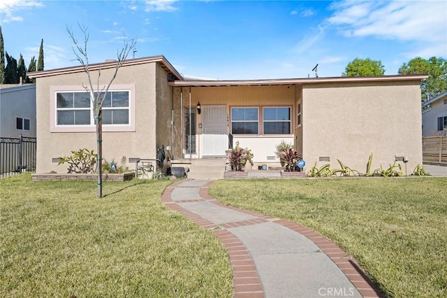 view of front facade featuring fence, a front lawn, and stucco siding