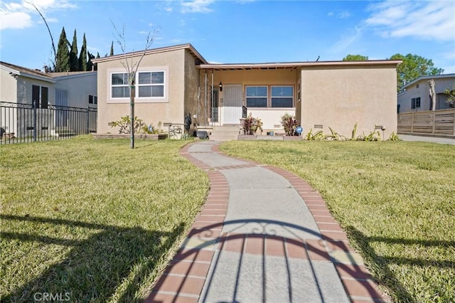 view of front of property featuring fence, a front lawn, and stucco siding