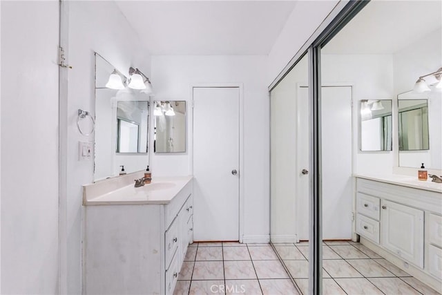 full bathroom featuring two vanities, tile patterned flooring, and a sink