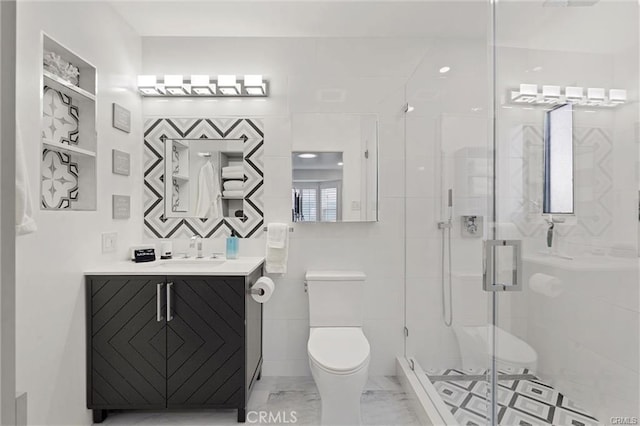 bathroom featuring marble finish floor, tile walls, toilet, a stall shower, and vanity