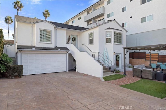 view of front of house featuring stairs, a pergola, an attached garage, and stucco siding