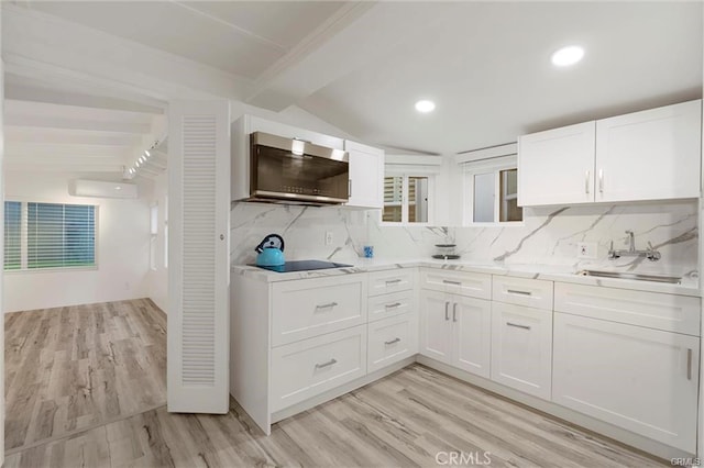 kitchen featuring white cabinets, decorative backsplash, stainless steel microwave, light countertops, and a wall mounted AC