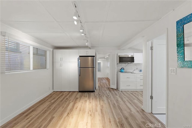 kitchen with light wood finished floors, rail lighting, white cabinetry, and freestanding refrigerator