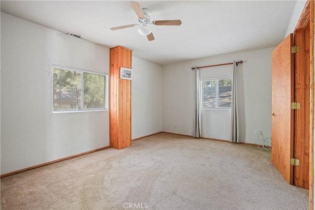 empty room with light carpet, ceiling fan, visible vents, and baseboards