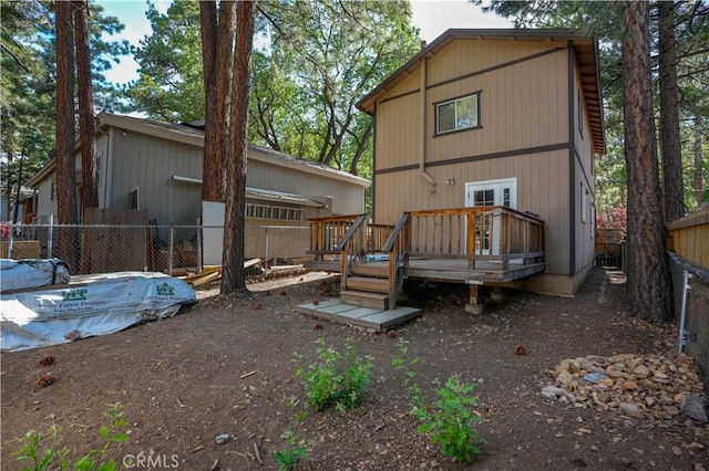 rear view of house featuring fence and a wooden deck