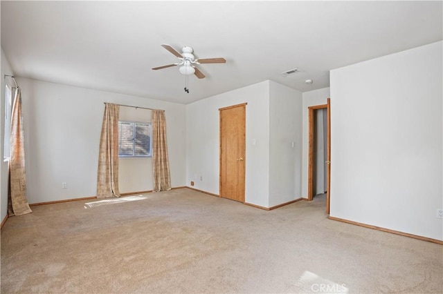 carpeted spare room featuring a ceiling fan, visible vents, and baseboards