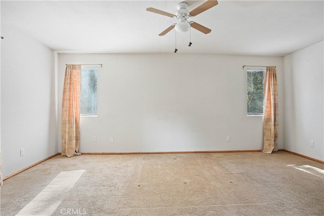 carpeted spare room with ceiling fan and baseboards