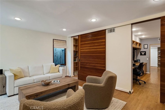 living area with light wood finished floors, baseboards, visible vents, built in shelves, and recessed lighting