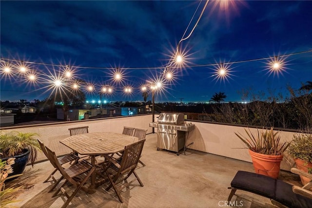 patio at twilight with outdoor dining area and area for grilling