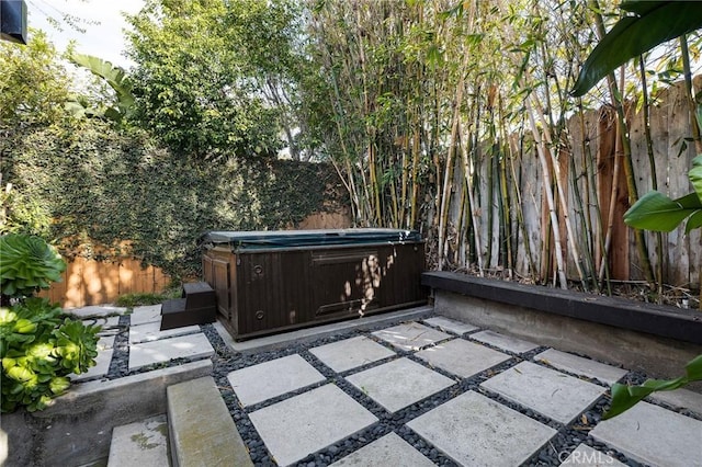 view of patio / terrace featuring fence and a hot tub