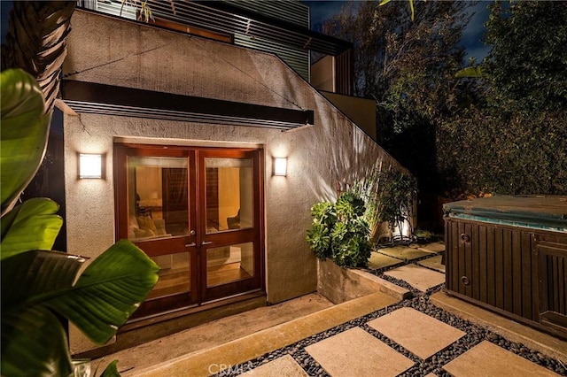 doorway to property with a patio area, a hot tub, and stucco siding