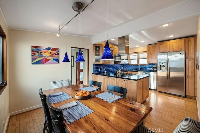 kitchen featuring island range hood, dark countertops, appliances with stainless steel finishes, a sink, and backsplash