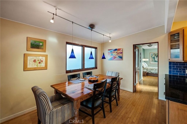 dining room featuring baseboards, track lighting, and light wood-style floors