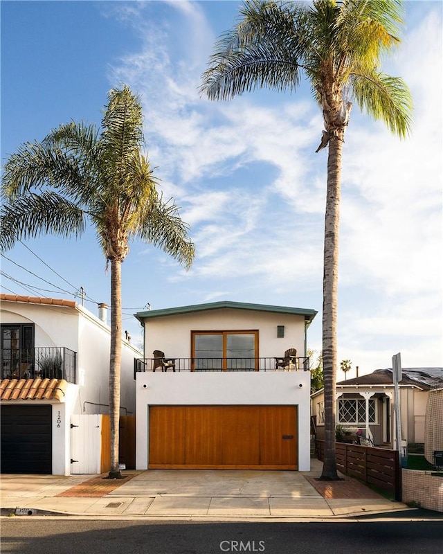 view of front facade featuring a gate, driveway, a balcony, and stucco siding