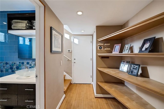 interior space featuring baseboards, stairway, light wood-type flooring, a sink, and recessed lighting