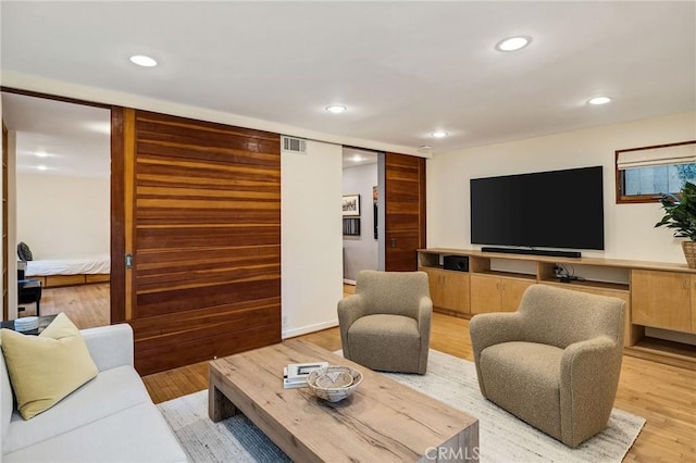 living room featuring light wood-type flooring, visible vents, and recessed lighting