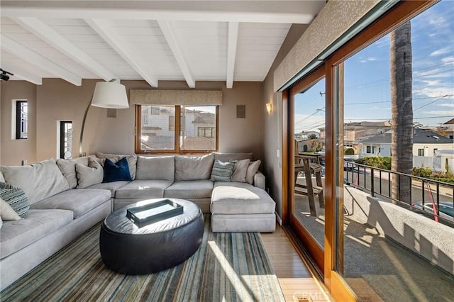 living area with beamed ceiling and wood finished floors