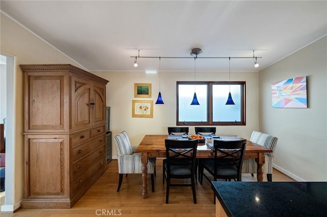 dining space featuring light wood-type flooring, rail lighting, and baseboards