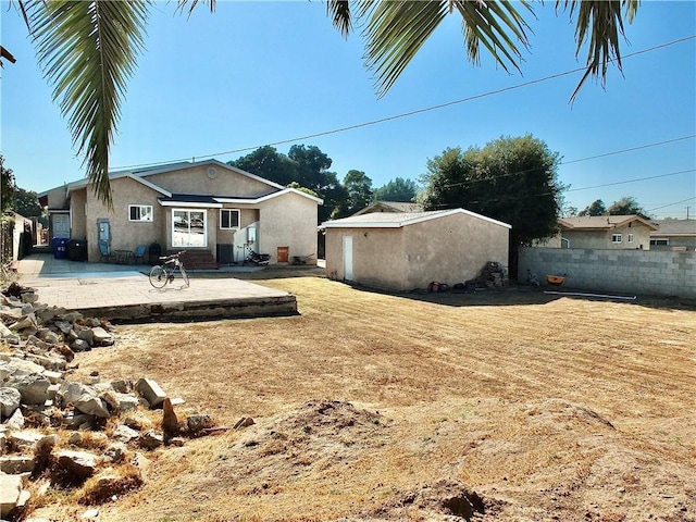 back of property with stucco siding, a yard, fence, and a patio