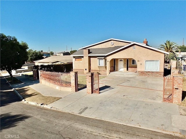 ranch-style home with driveway, a fenced front yard, a gate, and stucco siding