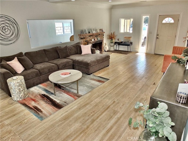 living area with a brick fireplace and wood finished floors