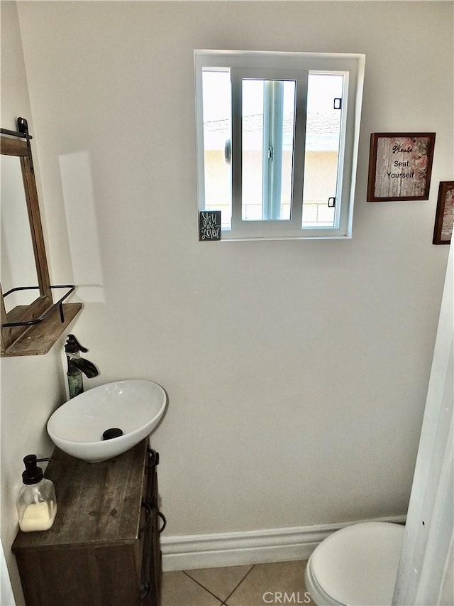 bathroom featuring toilet, tile patterned flooring, baseboards, and a sink