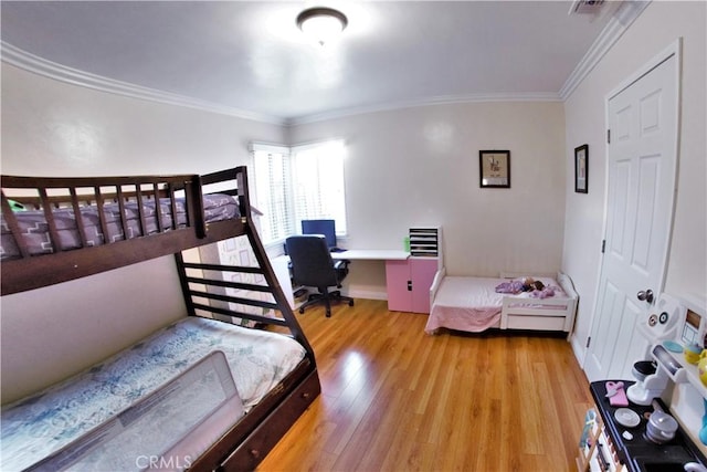 bedroom featuring visible vents, crown molding, baseboards, and wood finished floors