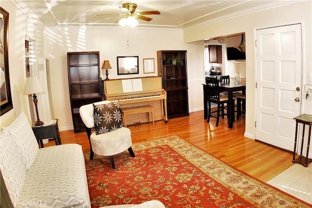 interior space featuring baseboards, a ceiling fan, crown molding, and wood finished floors