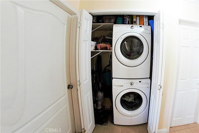 laundry room featuring stacked washer and clothes dryer, light tile patterned floors, and laundry area