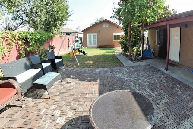 view of patio featuring a fenced backyard, an outdoor living space, a playground, and french doors