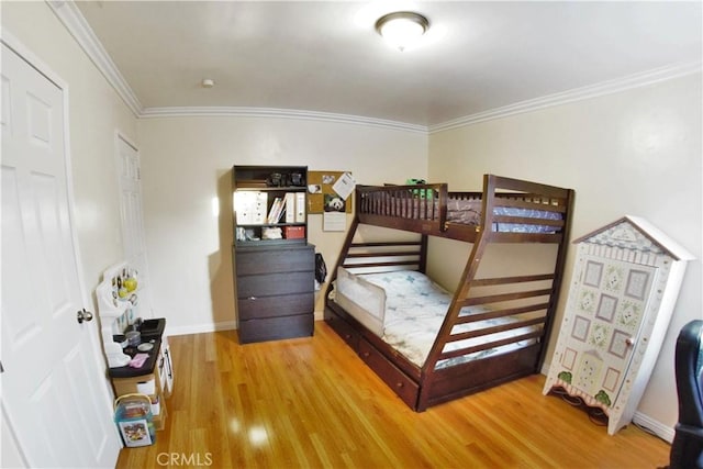 bedroom featuring light wood-style flooring, ornamental molding, and baseboards