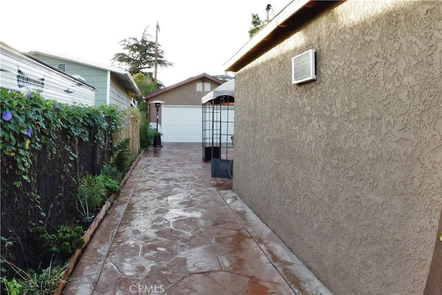 view of home's exterior featuring a garage, an outdoor structure, fence, and stucco siding