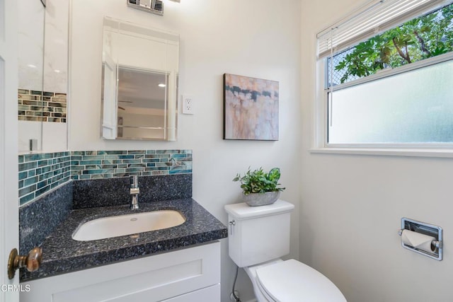 half bath with vanity, toilet, and backsplash