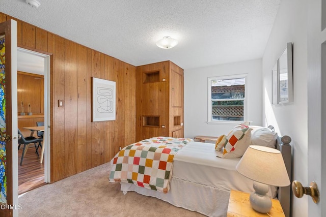 carpeted bedroom featuring wooden walls and a textured ceiling