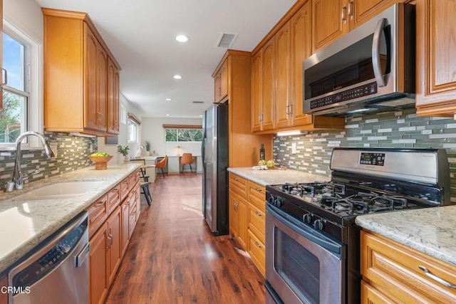 kitchen with dark wood-style floors, light stone countertops, recessed lighting, a sink, and stainless steel appliances