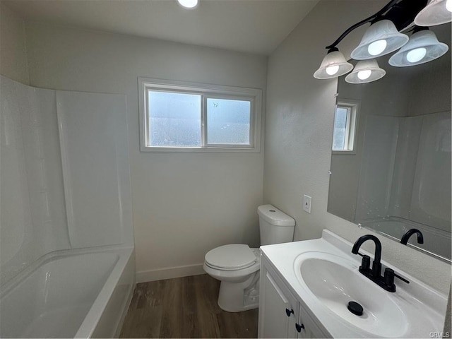 full bathroom featuring toilet, a healthy amount of sunlight, wood finished floors, and vanity