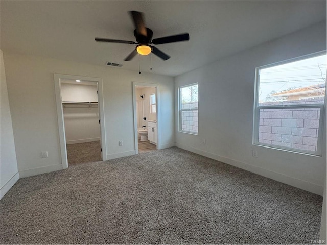 unfurnished bedroom with carpet floors, visible vents, a spacious closet, and baseboards