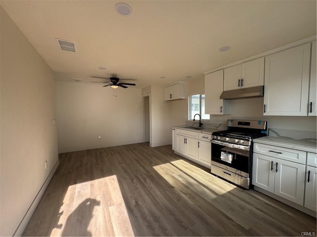 kitchen with stainless steel gas stove, visible vents, white cabinets, under cabinet range hood, and a sink