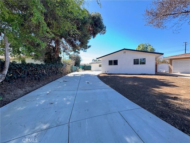 view of side of property with driveway, a gate, fence, and stucco siding