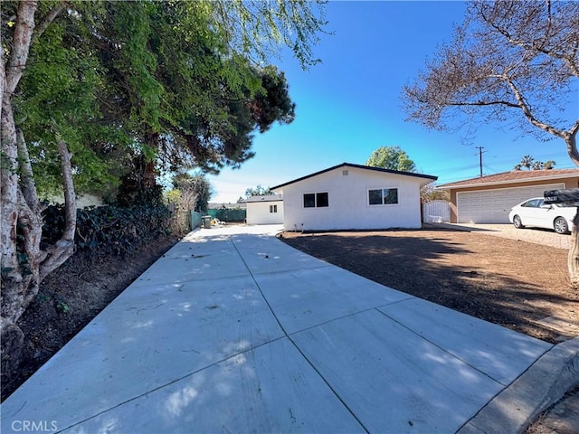 exterior space with an outbuilding, concrete driveway, fence, and stucco siding