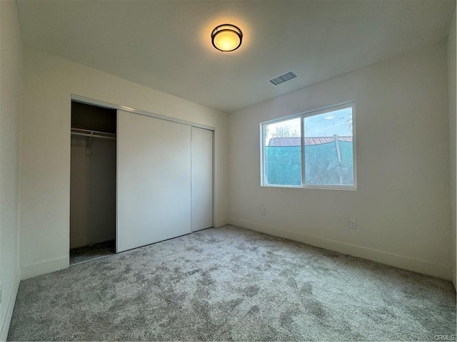 unfurnished bedroom featuring baseboards, carpet, visible vents, and a closet