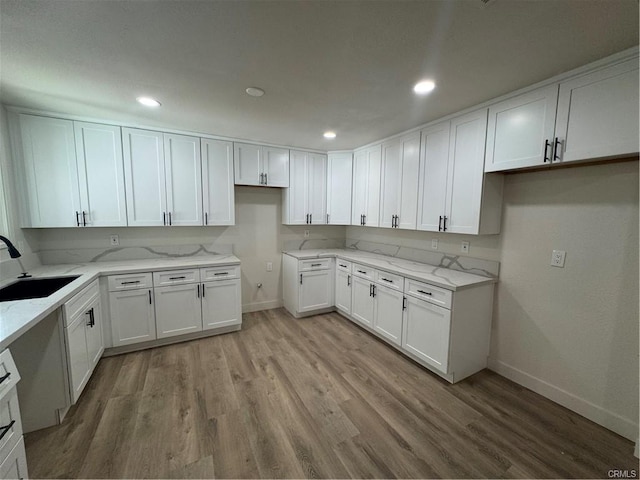 kitchen with a sink, white cabinets, and light stone countertops