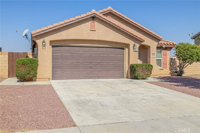 view of front facade with an attached garage, a tile roof, fence, concrete driveway, and stucco siding