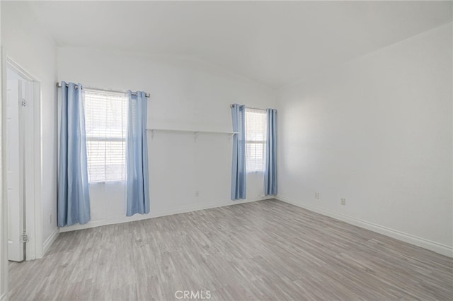 empty room with lofted ceiling, baseboards, and wood finished floors