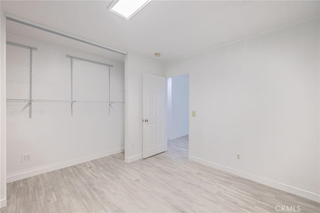 unfurnished bedroom with a closet, wood finished floors, and baseboards