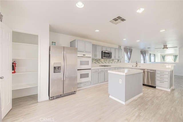 kitchen featuring a wealth of natural light, appliances with stainless steel finishes, gray cabinets, and visible vents