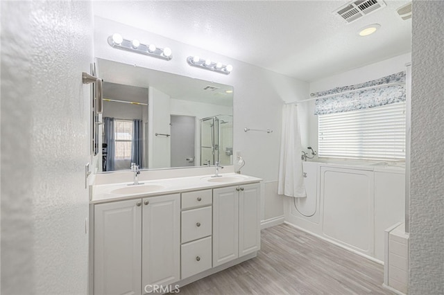 bathroom featuring wood finished floors, curtained shower, a sink, and visible vents