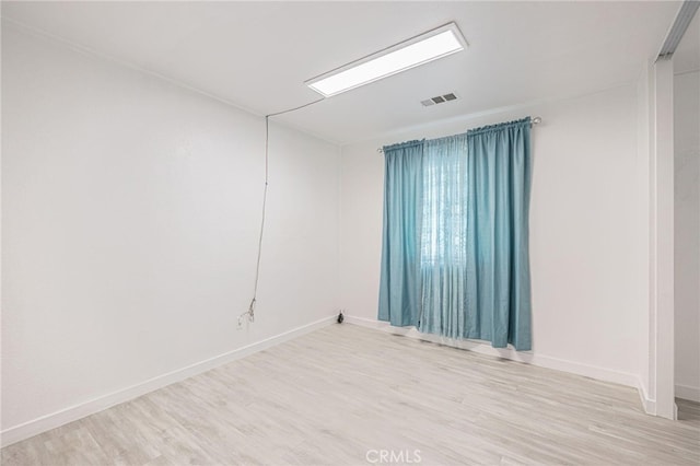 unfurnished room with baseboards, visible vents, and wood finished floors